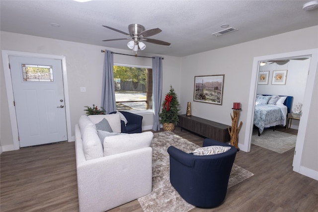 living room featuring ceiling fan, a textured ceiling, visible vents, and wood finished floors