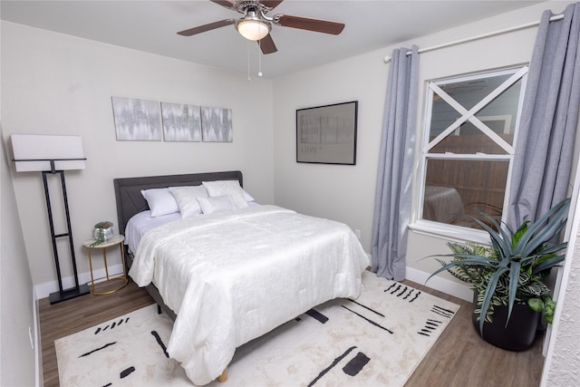 bedroom with ceiling fan, baseboards, and wood finished floors