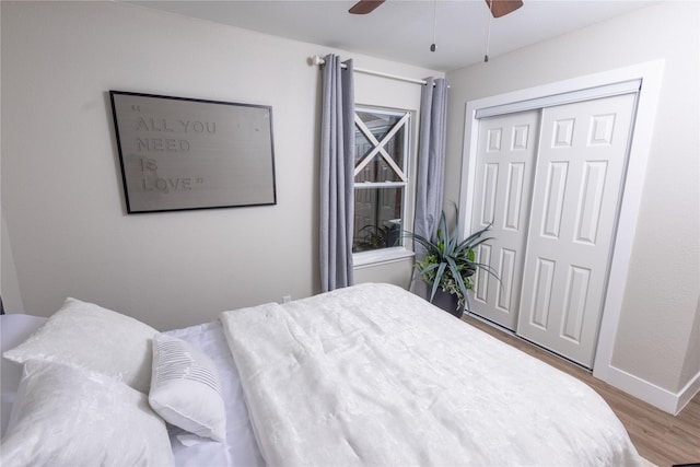 bedroom featuring a ceiling fan, a closet, light wood-style flooring, and baseboards