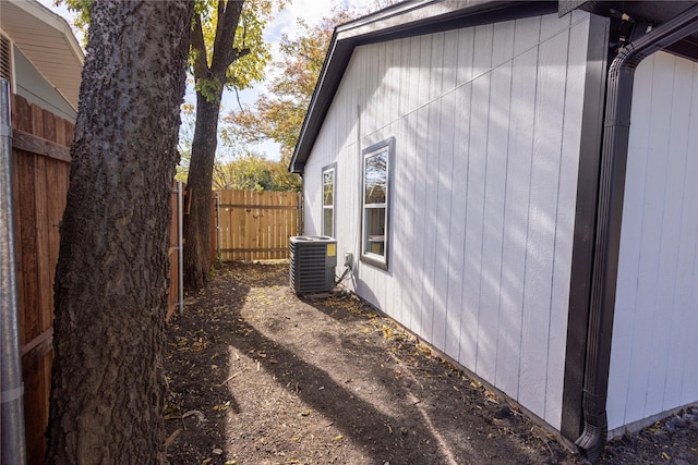 view of side of home with cooling unit and fence