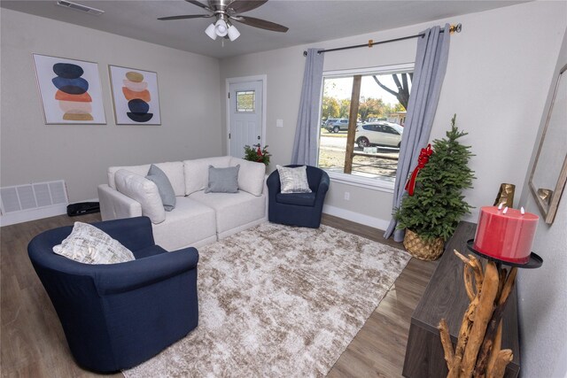 living area featuring ceiling fan, wood finished floors, visible vents, and baseboards