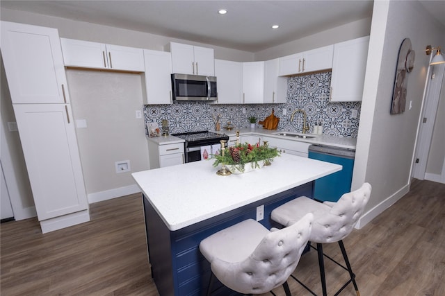 kitchen featuring dark wood-type flooring, white cabinetry, stainless steel appliances, and a sink