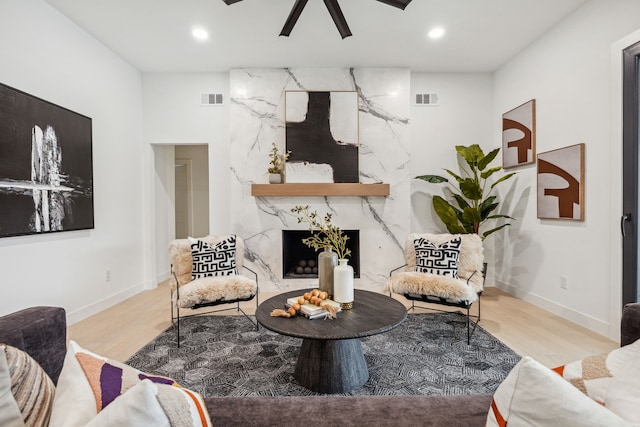 living room with ceiling fan, light hardwood / wood-style flooring, and a high end fireplace