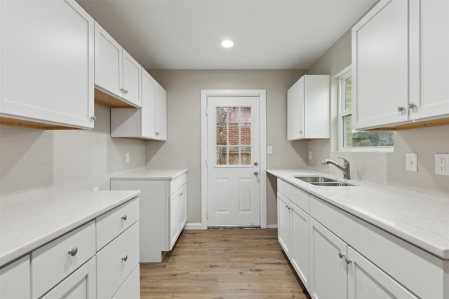 kitchen featuring recessed lighting, white cabinets, a sink, and light wood finished floors