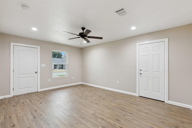 empty room with a ceiling fan, light wood-type flooring, visible vents, and baseboards