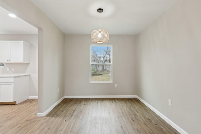 unfurnished dining area with baseboards and light wood finished floors