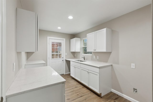 kitchen featuring white cabinets, a sink, and light wood finished floors