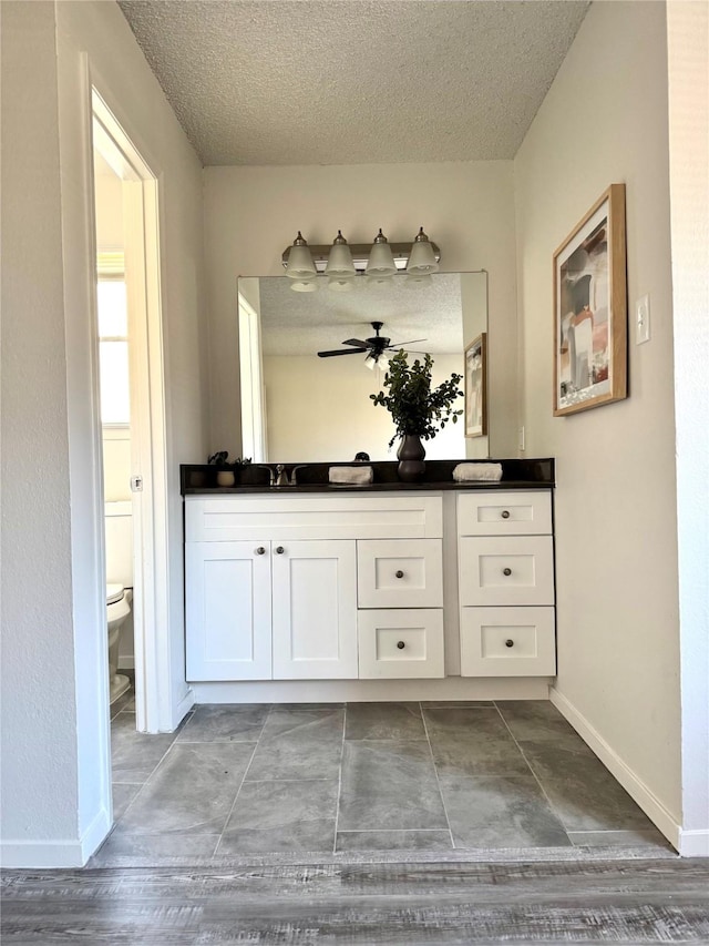 bathroom featuring a textured ceiling, toilet, and vanity