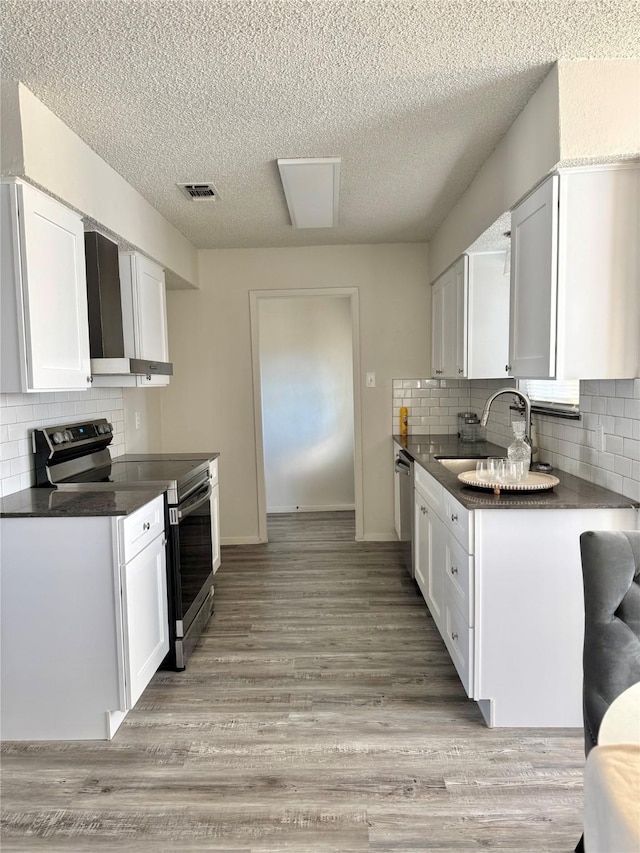 kitchen featuring sink, wall chimney exhaust hood, stainless steel appliances, and white cabinets