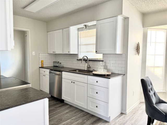 kitchen featuring white cabinetry, light wood-type flooring, sink, stainless steel dishwasher, and a textured ceiling