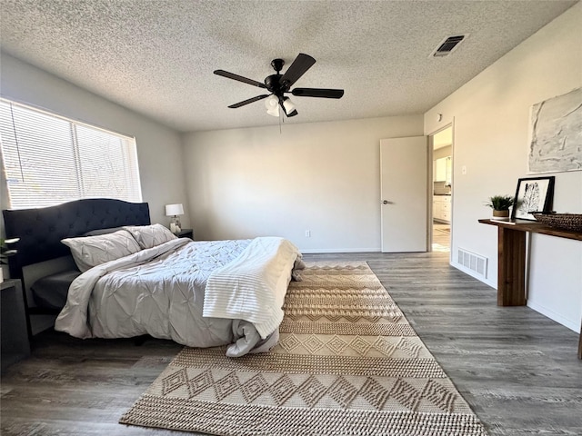 bedroom with a textured ceiling, ceiling fan, and dark hardwood / wood-style floors