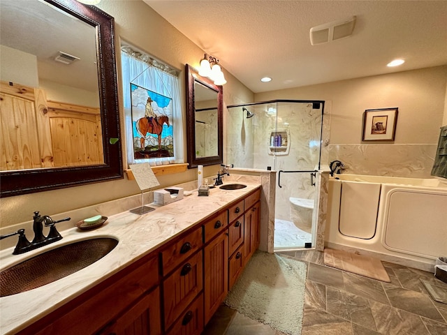 bathroom with a textured ceiling, vanity, and independent shower and bath