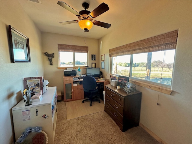 carpeted office space with ceiling fan