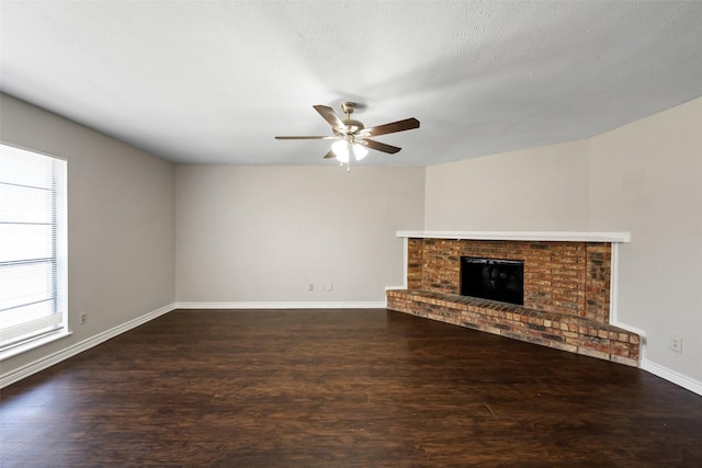 unfurnished living room with a fireplace, ceiling fan, dark hardwood / wood-style floors, and a textured ceiling