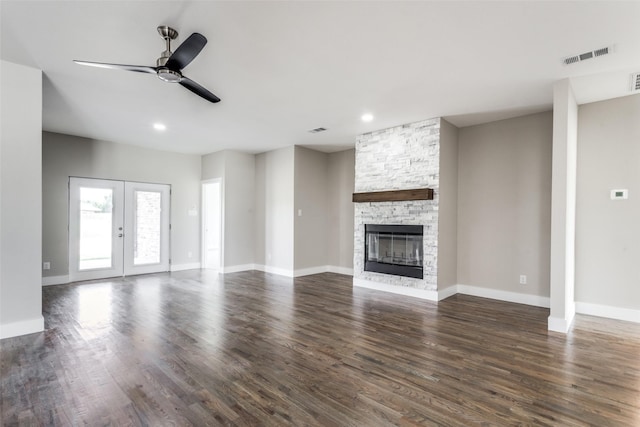 unfurnished living room with ceiling fan, french doors, dark wood-type flooring, and a fireplace