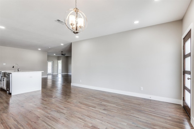 unfurnished living room featuring light hardwood / wood-style floors and ceiling fan with notable chandelier