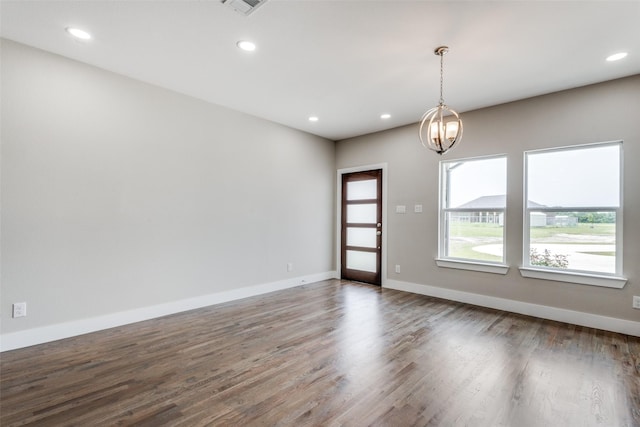 empty room featuring a chandelier and dark hardwood / wood-style floors