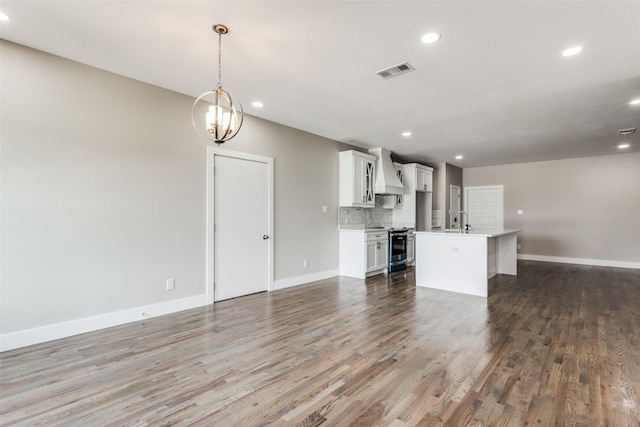 unfurnished living room featuring dark hardwood / wood-style flooring, sink, and a chandelier