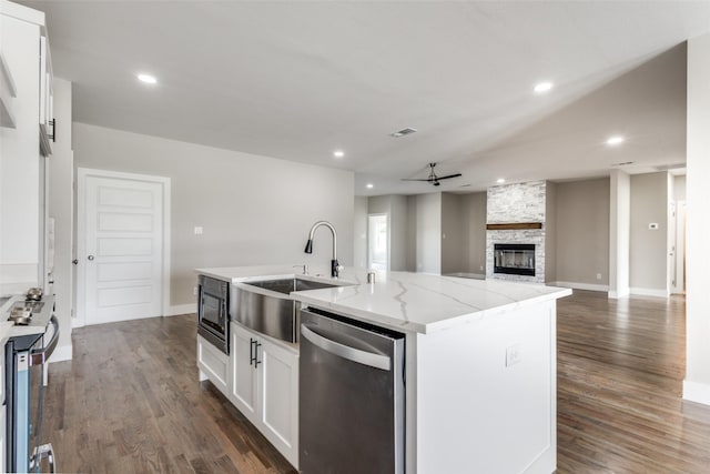 kitchen with a kitchen island with sink, dishwasher, ceiling fan, light stone counters, and white cabinets