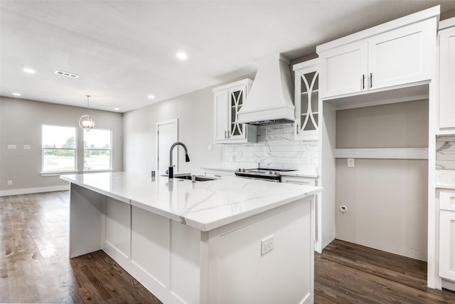 kitchen featuring custom exhaust hood, white cabinets, a kitchen island with sink, and stainless steel range with electric cooktop