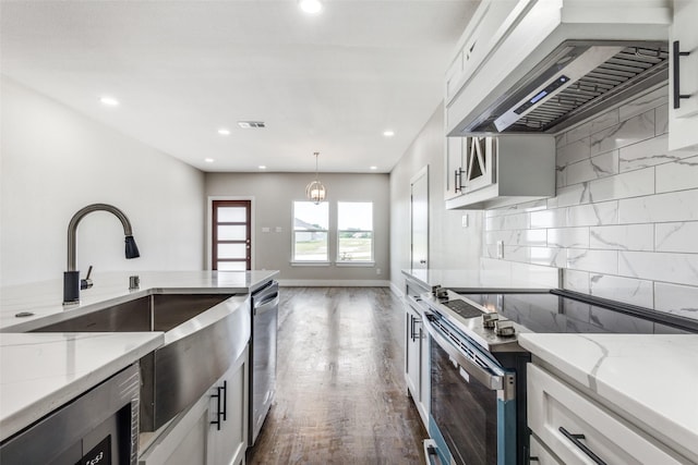 kitchen featuring appliances with stainless steel finishes, light stone countertops, custom range hood, and white cabinets