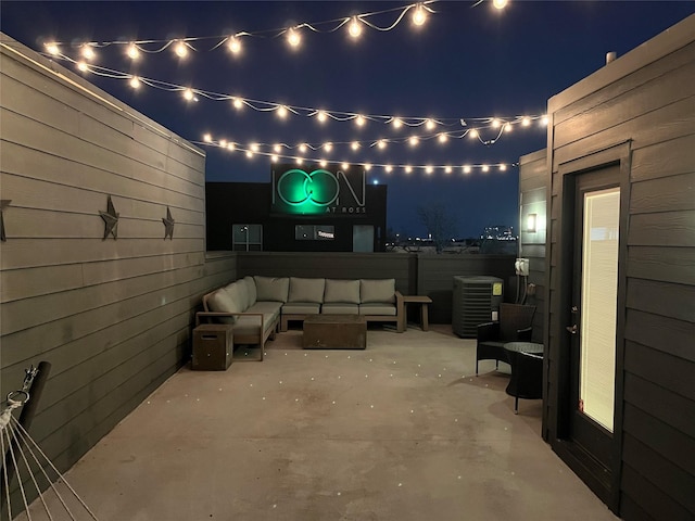 patio at night with fence and an outdoor hangout area