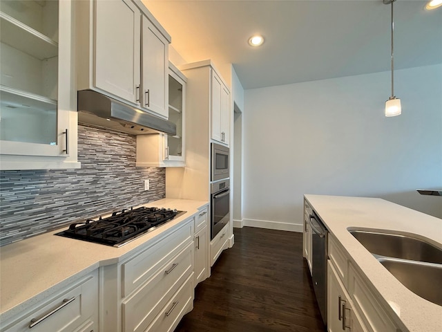 kitchen featuring appliances with stainless steel finishes, sink, pendant lighting, white cabinets, and decorative backsplash