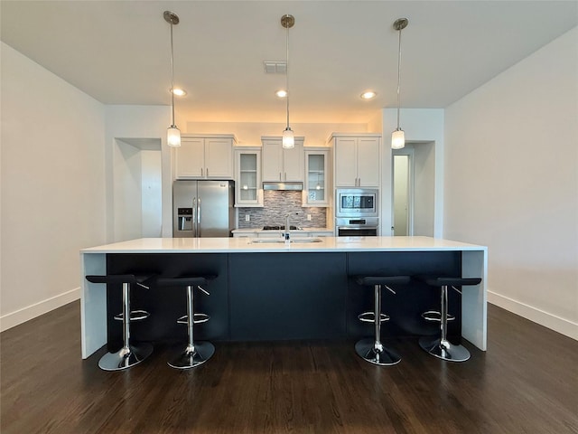 kitchen with a breakfast bar, light countertops, decorative backsplash, appliances with stainless steel finishes, and a large island