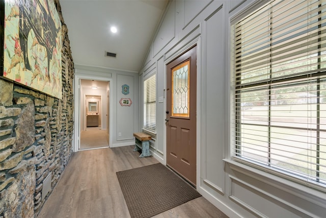 entryway with visible vents, vaulted ceiling, and wood finished floors