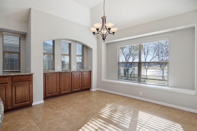 unfurnished dining area featuring a notable chandelier, light tile patterned floors, and vaulted ceiling