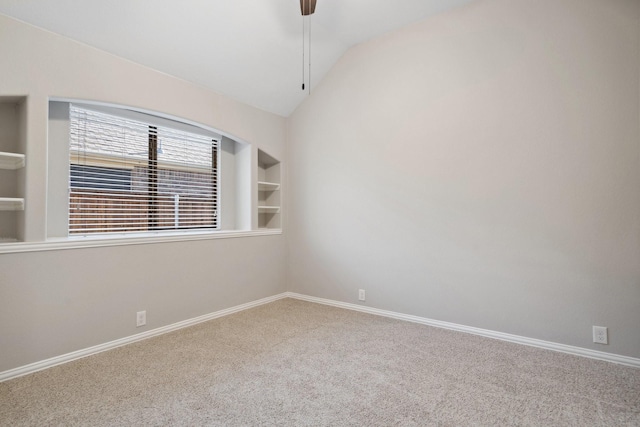 empty room featuring carpet flooring, vaulted ceiling, and built in features