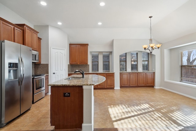 kitchen with appliances with stainless steel finishes, sink, lofted ceiling, pendant lighting, and light stone countertops