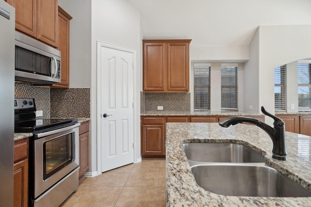 kitchen featuring sink, a healthy amount of sunlight, stainless steel appliances, and light stone counters