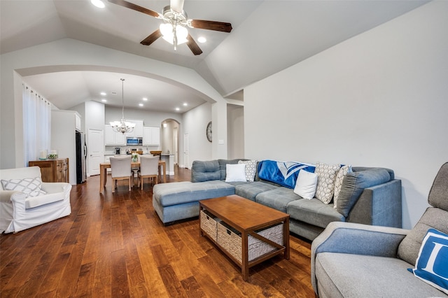 living area featuring vaulted ceiling, dark wood-style flooring, ceiling fan with notable chandelier, and arched walkways