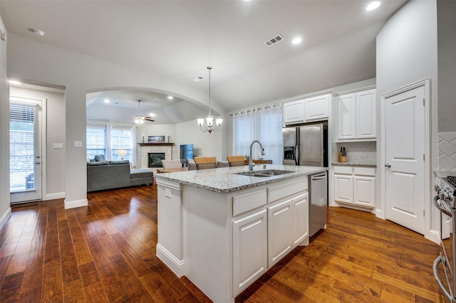 kitchen with white cabinets, an island with sink, appliances with stainless steel finishes, open floor plan, and light stone countertops