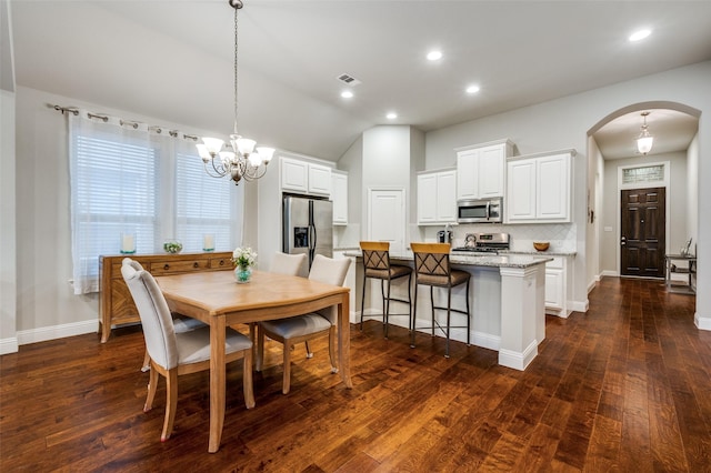 dining area with arched walkways, dark wood-style floors, visible vents, and baseboards