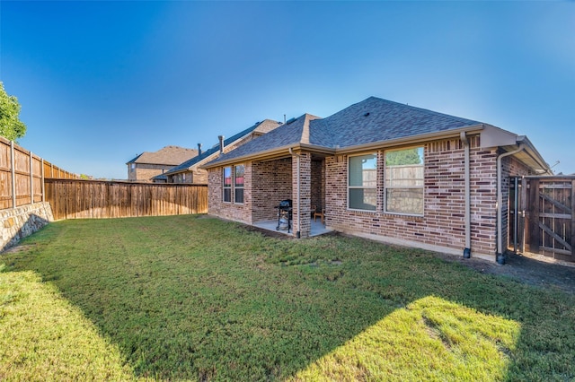 rear view of house featuring a yard, brick siding, and a fenced backyard