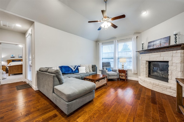 living area featuring dark wood-style floors, a fireplace, visible vents, vaulted ceiling, and baseboards