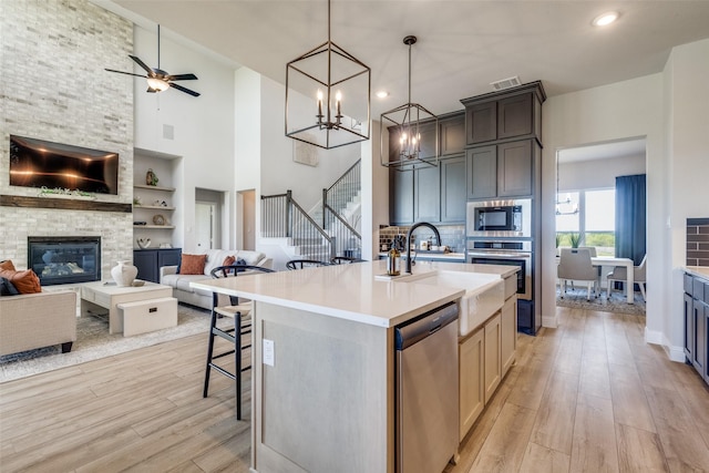 kitchen with appliances with stainless steel finishes, light wood-type flooring, open floor plan, and a fireplace