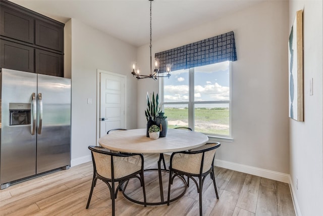 dining room featuring baseboards, an inviting chandelier, and light wood-style floors