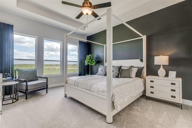 bedroom with a ceiling fan, a raised ceiling, carpet flooring, and baseboards