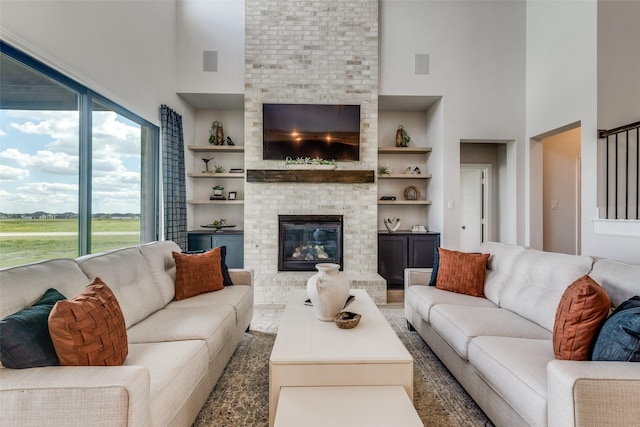 living room featuring built in shelves, a fireplace, and a high ceiling
