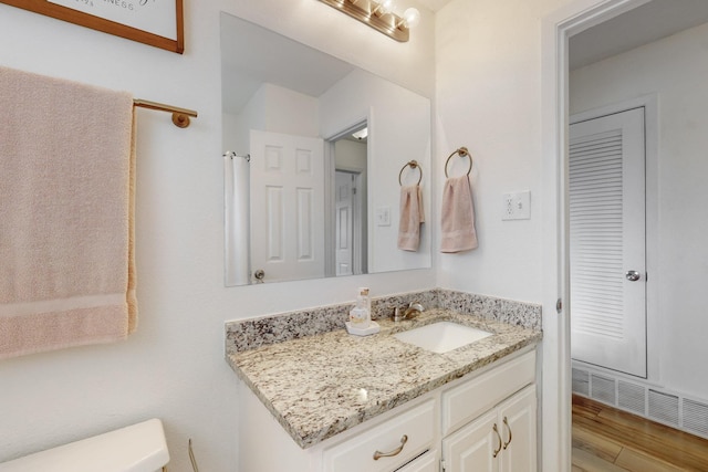 bathroom with hardwood / wood-style floors, toilet, and vanity