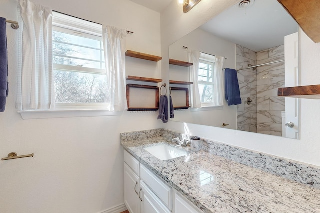 bathroom with a tile shower and vanity