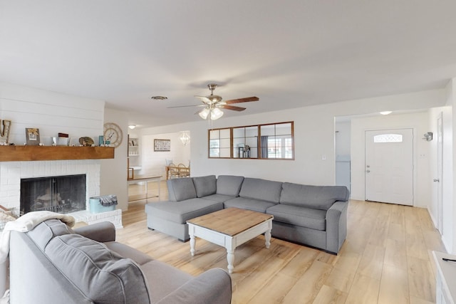 living room with a fireplace, ceiling fan, and light hardwood / wood-style floors