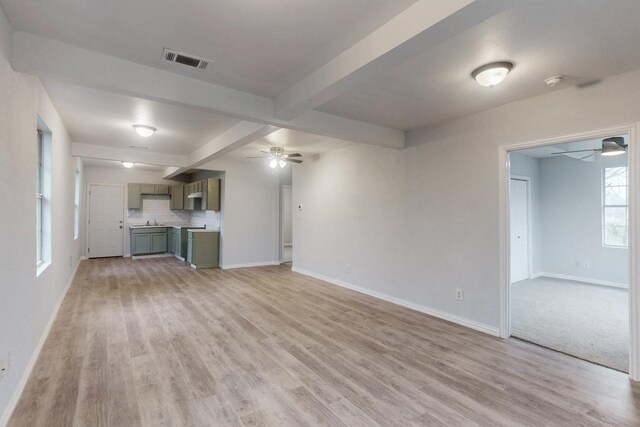 505 Oak St, Commerce, TX 75428 - unfurnished living room with a ceiling fan, beamed ceiling, light wood finished floors, and baseboards