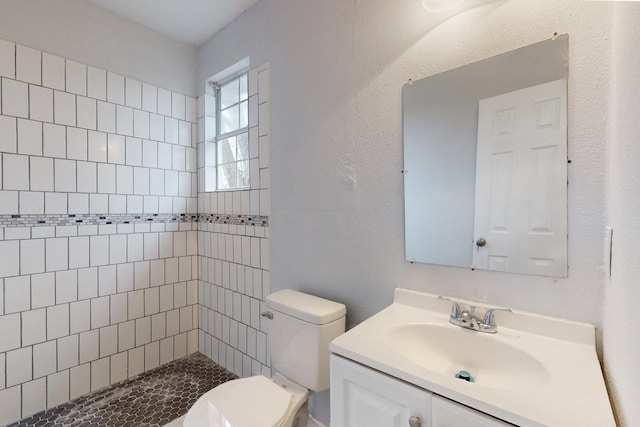 bathroom featuring vanity, tiled shower, and toilet