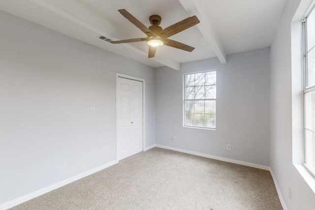 spare room with ceiling fan, beamed ceiling, and carpet flooring