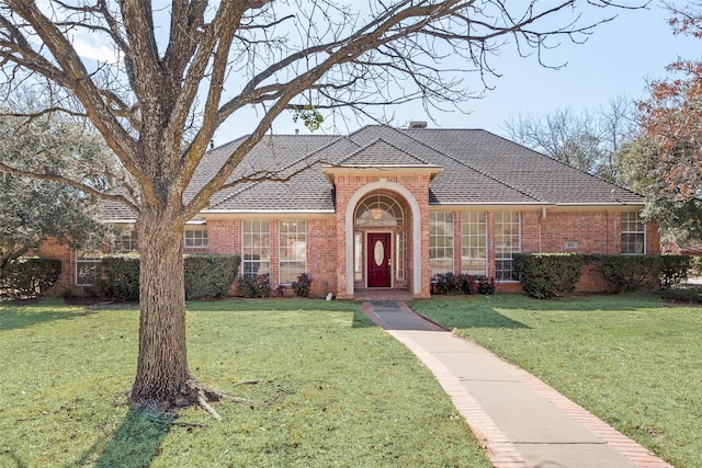 view of front of house with brick siding, a chimney, and a front yard