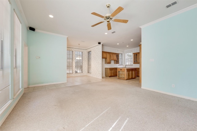 unfurnished living room featuring light carpet, baseboards, visible vents, crown molding, and ceiling fan with notable chandelier